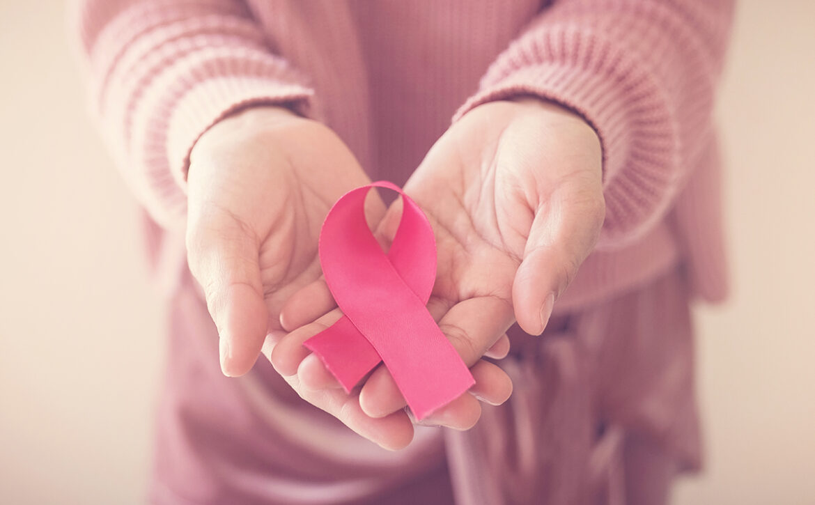 woman wearing pink top with pink ribbon, breast cancer awareness