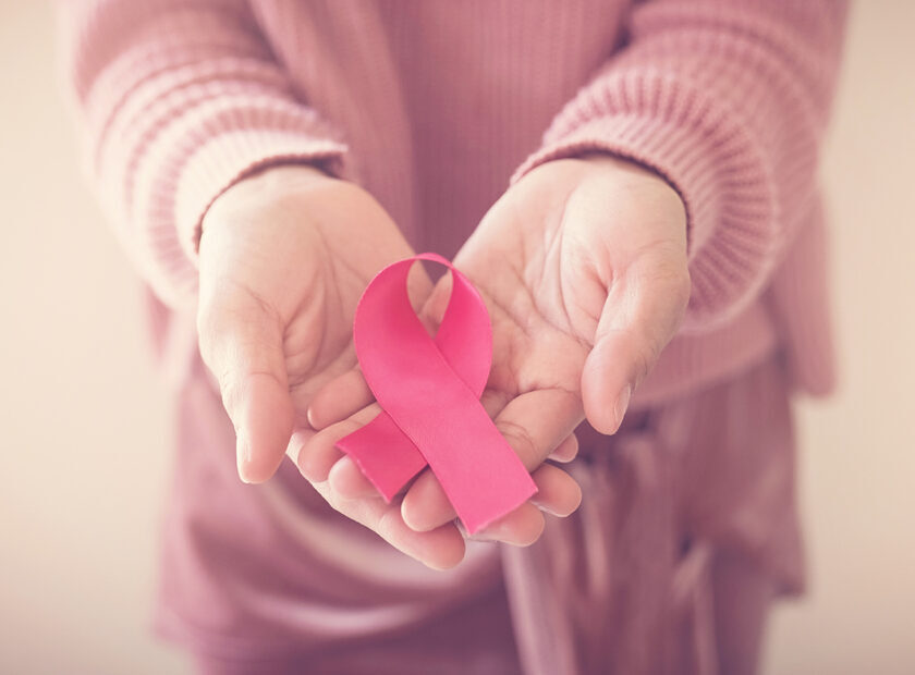 woman wearing pink top with pink ribbon, breast cancer awareness